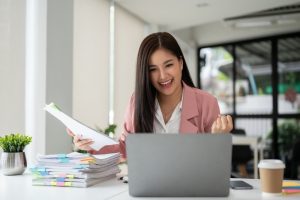 a cheerful and successful asian businesswoman looking at her laptop