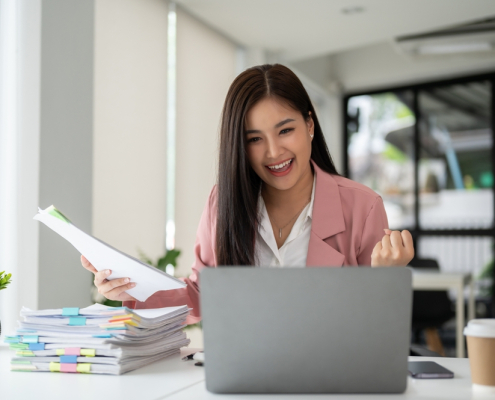 a cheerful and successful asian businesswoman looking at her laptop