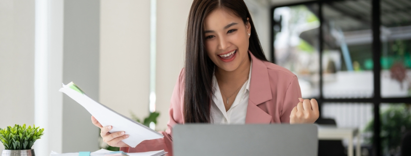 a cheerful and successful asian businesswoman looking at her laptop