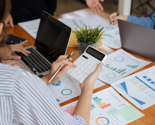 Businesswoman,Using,A,Calculator,To,Calculate,Numbers,On,A,Company's