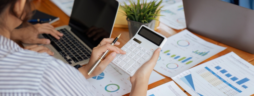 Businesswoman,Using,A,Calculator,To,Calculate,Numbers,On,A,Company's