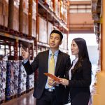 Asian two business people discussing of product at storage wareh