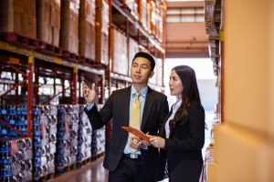 Asian two business people discussing of product at storage wareh